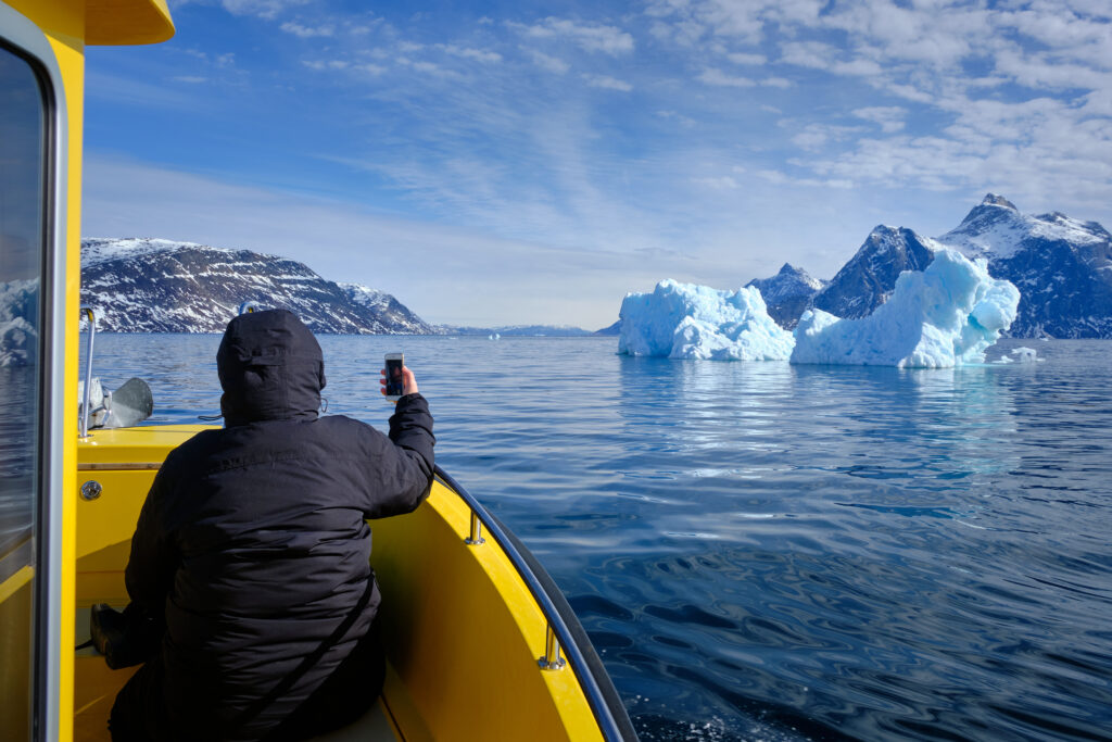 Passenger taking a photo of a large iceberg on a boat tour to the Nuuk Icefjord with Guide to Greenland