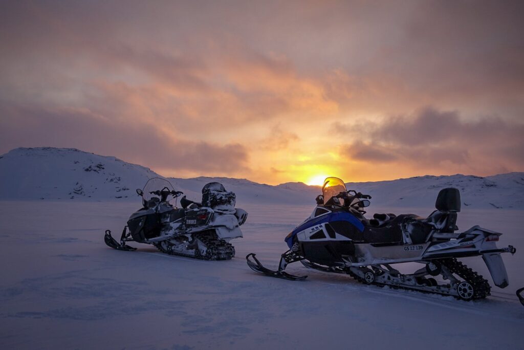 Snowmobiles with a sunset in the background
