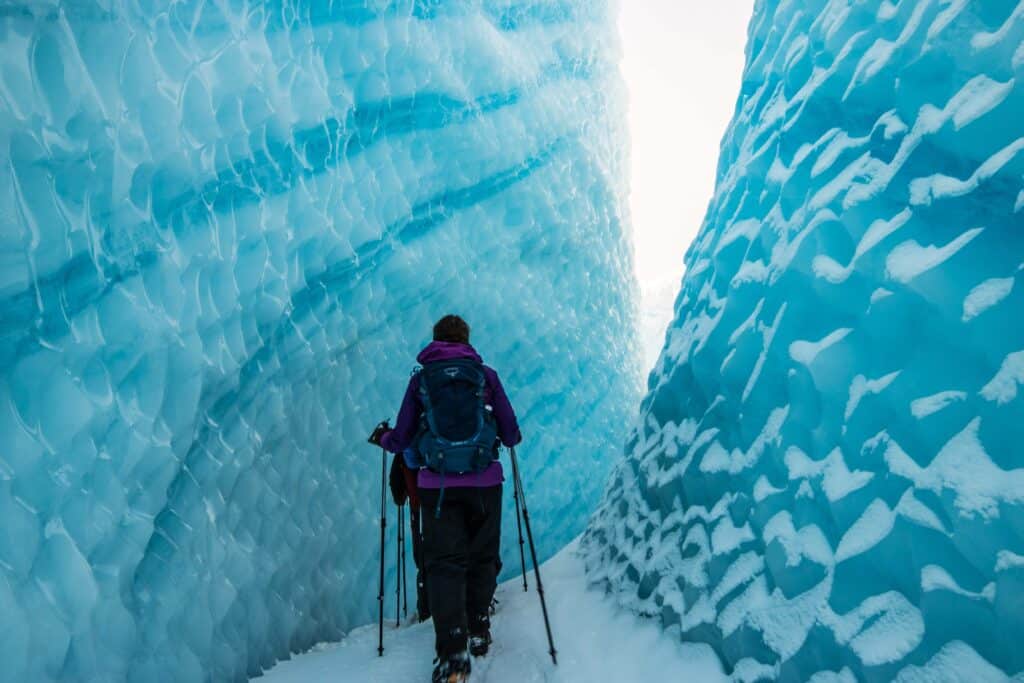 Two hikers walking between to large chunks of ice