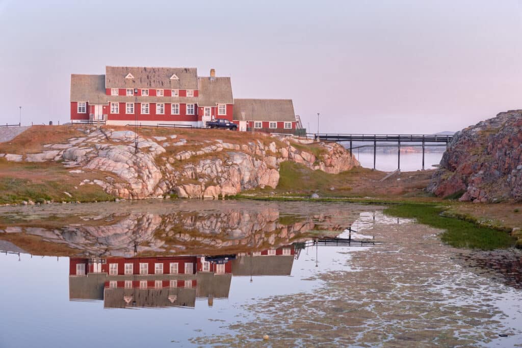 Aasiaat's town library reflected in the lake at sunrise