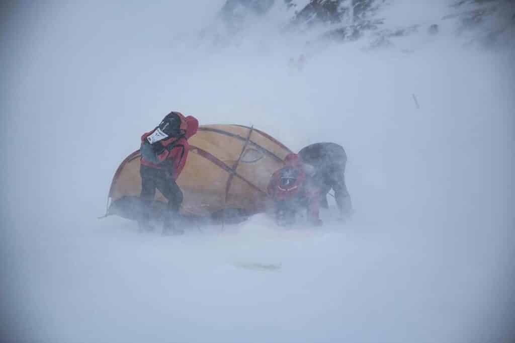 Workers trying to hold down a tent during a snow storm during Arctic Circle Race