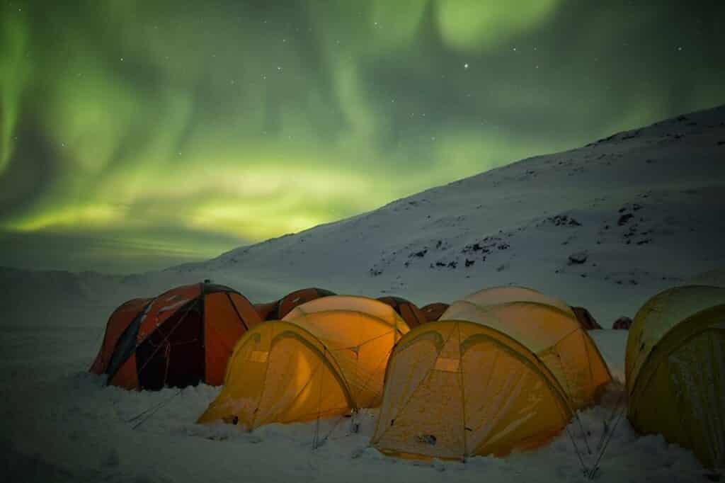 Northern lights over yellow and red tents