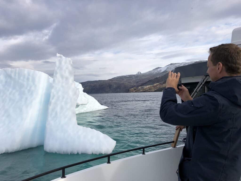 Man taking a picture of an iceberg