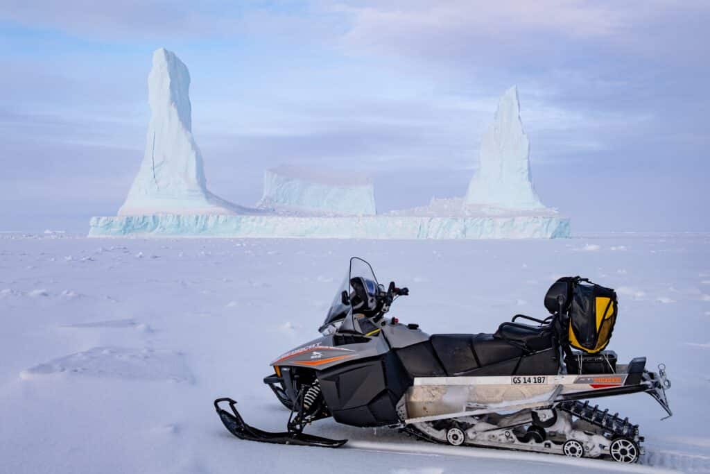 Snowmobile in front of a large iceberg