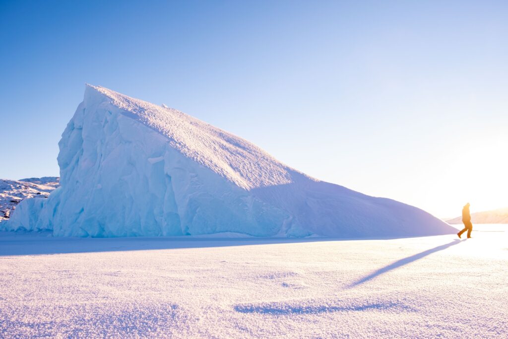Man walking past a large iceberg