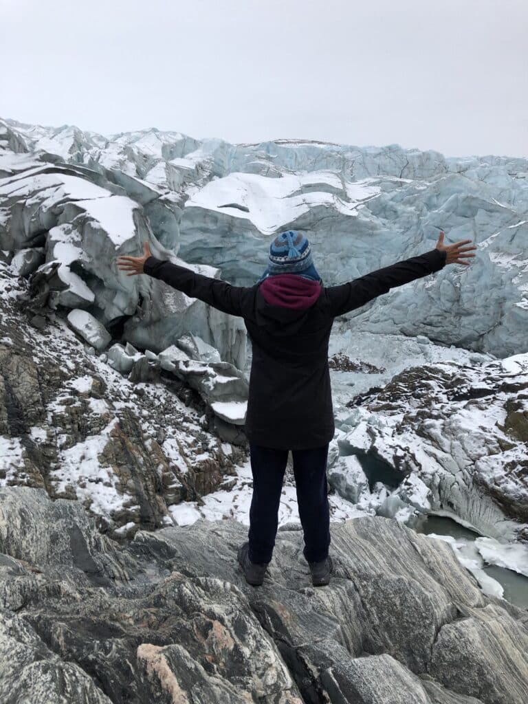 Woman standing in front of a glacier in Greenland