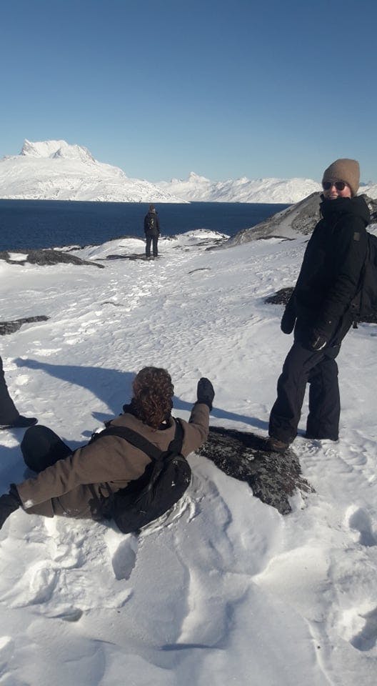 A woman in deep snow and her friend laughing at her