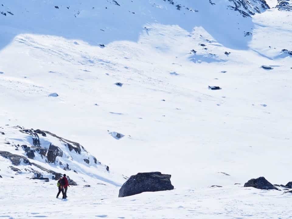 Two people walking in the snow masses