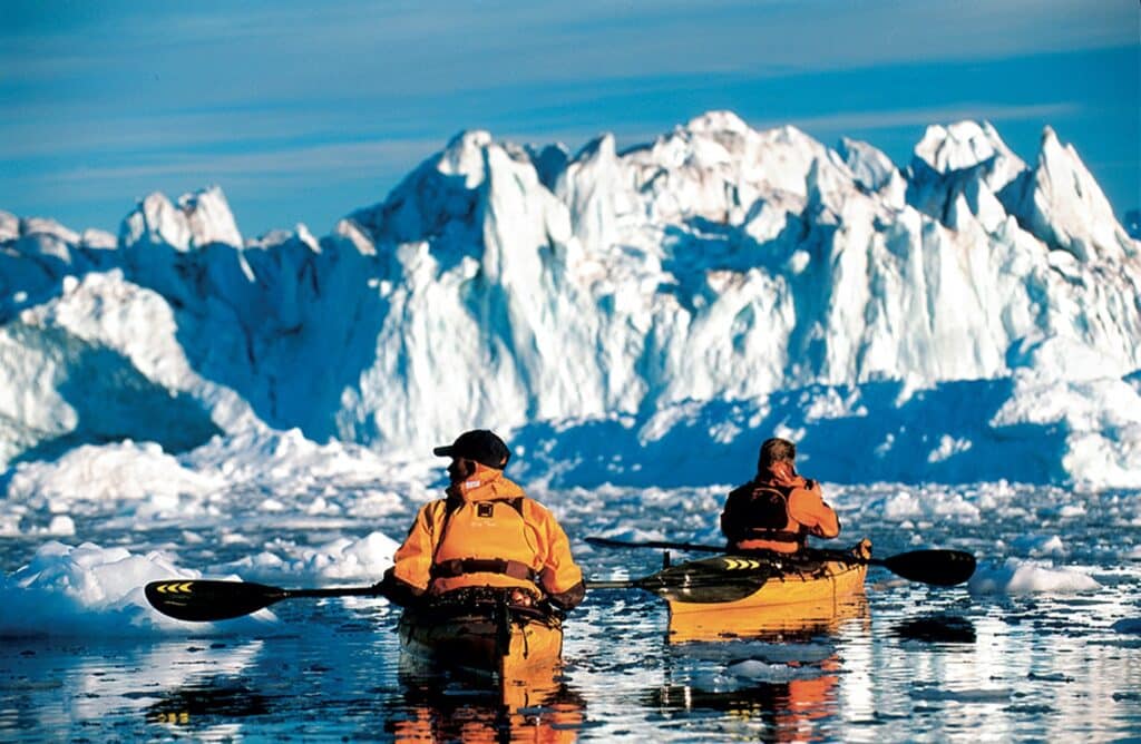 Couple kayaking among icebergs in Greenland