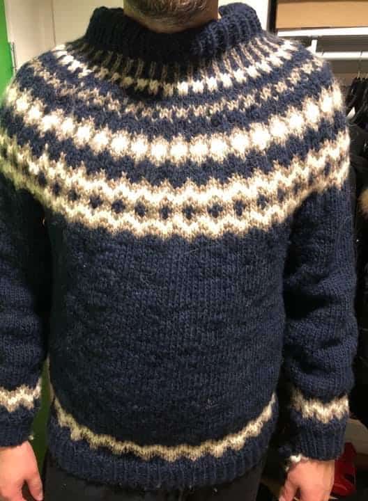 Man displaying a finished sweater in knit