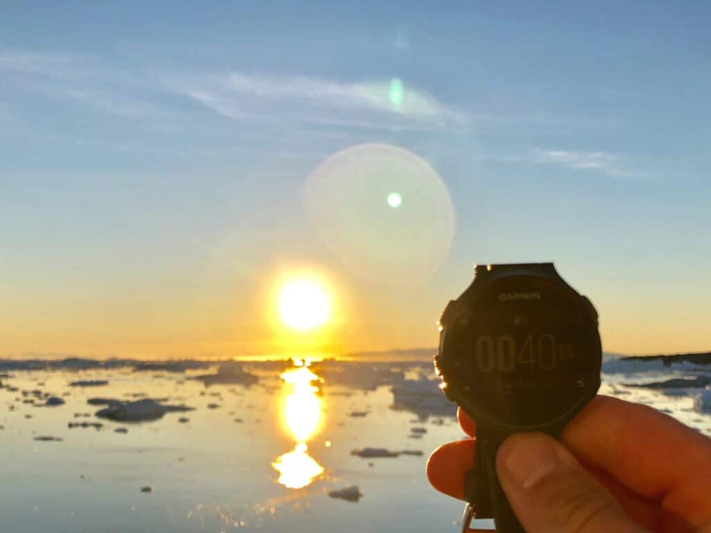 A watch being held up next to the midnight sun