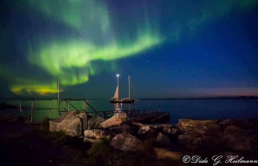Northern lights dancing over a boat in the fjord