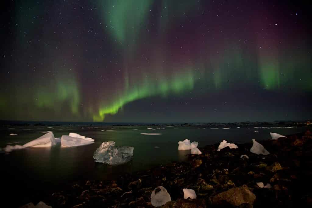 Green and purple northern lights over the icefjord in Greenland