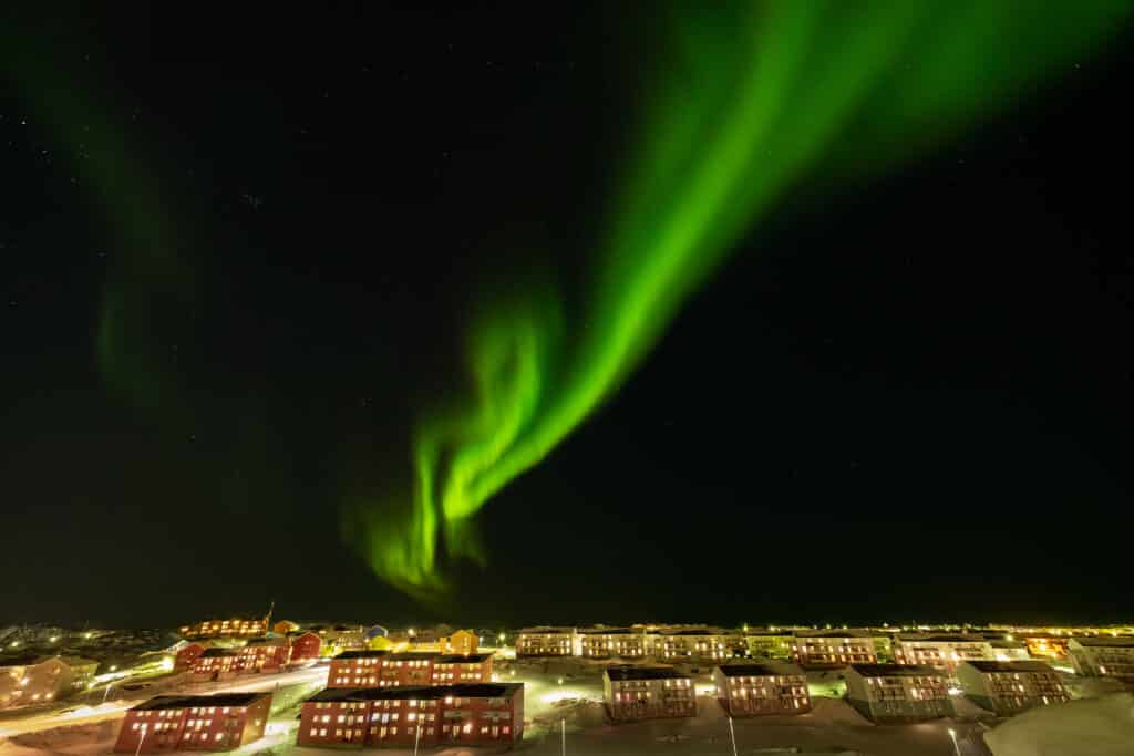 Northern Lights over red apartment buildings in Nuuk, capital of Greenland