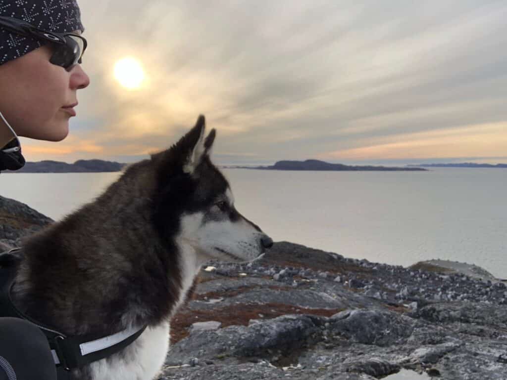 Dog and woman looking over the fjord