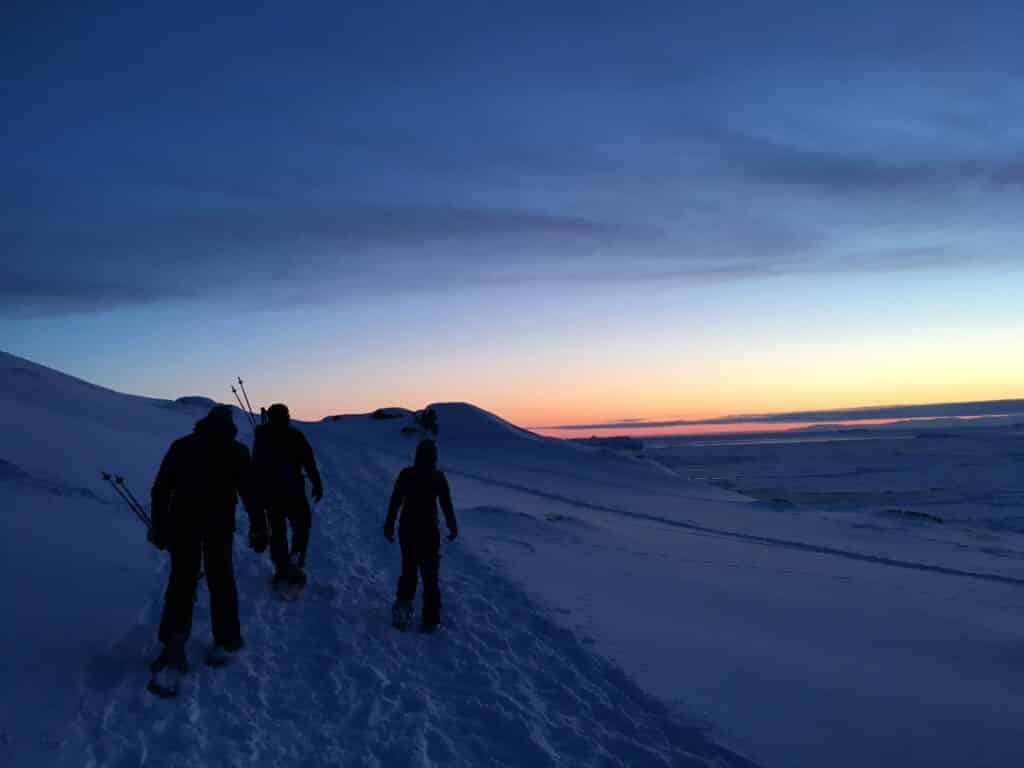 People snowshoeing under a red sky