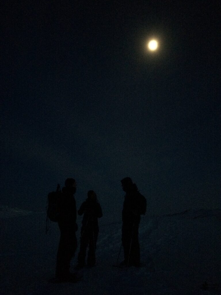 People standing in the dark under the moon