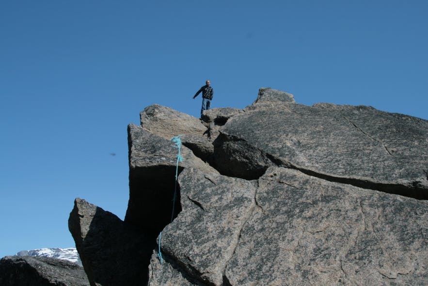 Man on top of a large rock in the south of Greenland