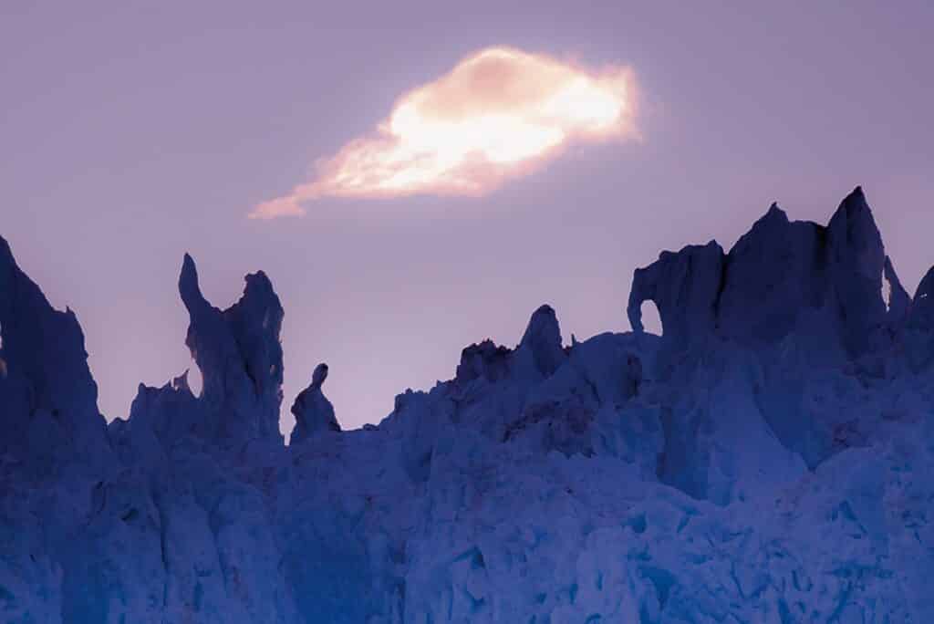 Cloud blocking the sun thus creating a purple looking sky over a glacier in Greenland