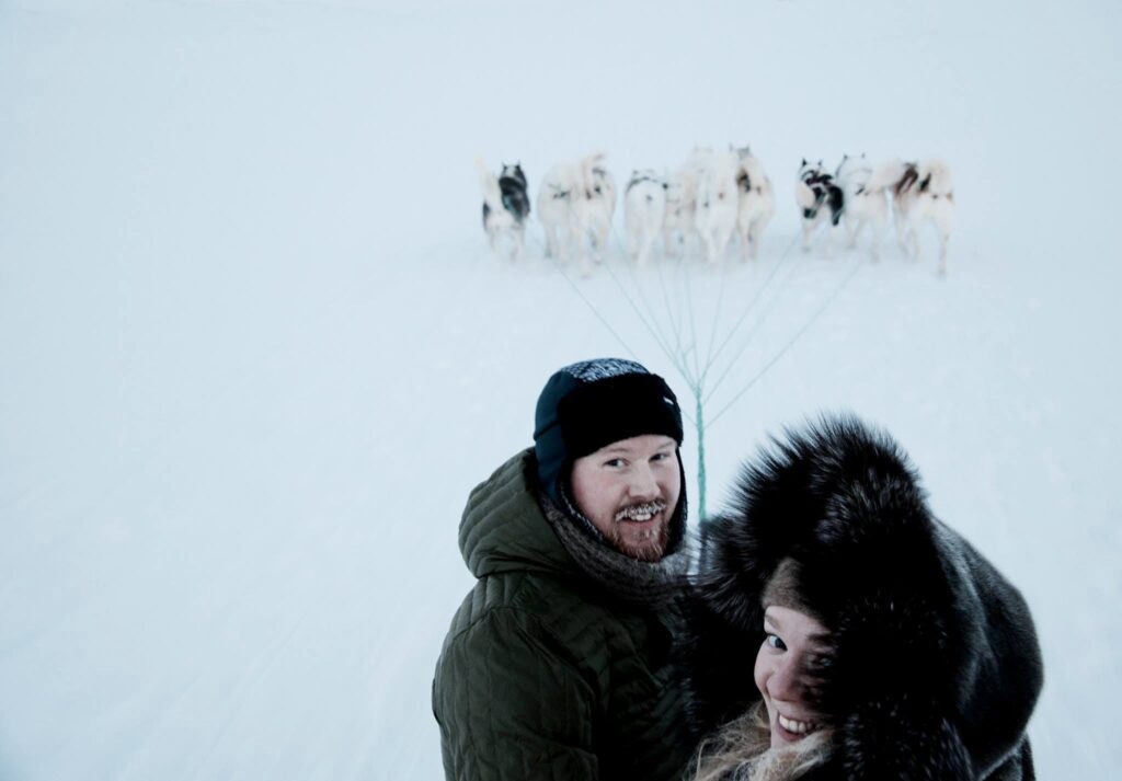 Couple standing in front of a pack of sled dogs