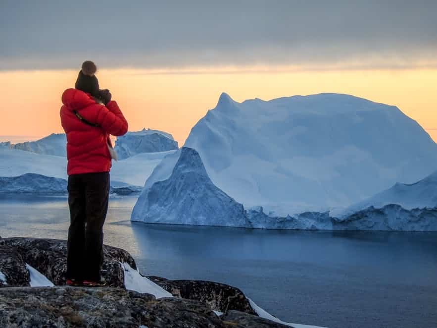 person taking photos of massive icebergs in Ilulissat - Guide to Greenland
