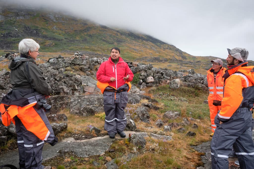 Guide explaining some of the other ruins at the Hvalsey Church site - Qaqortoq