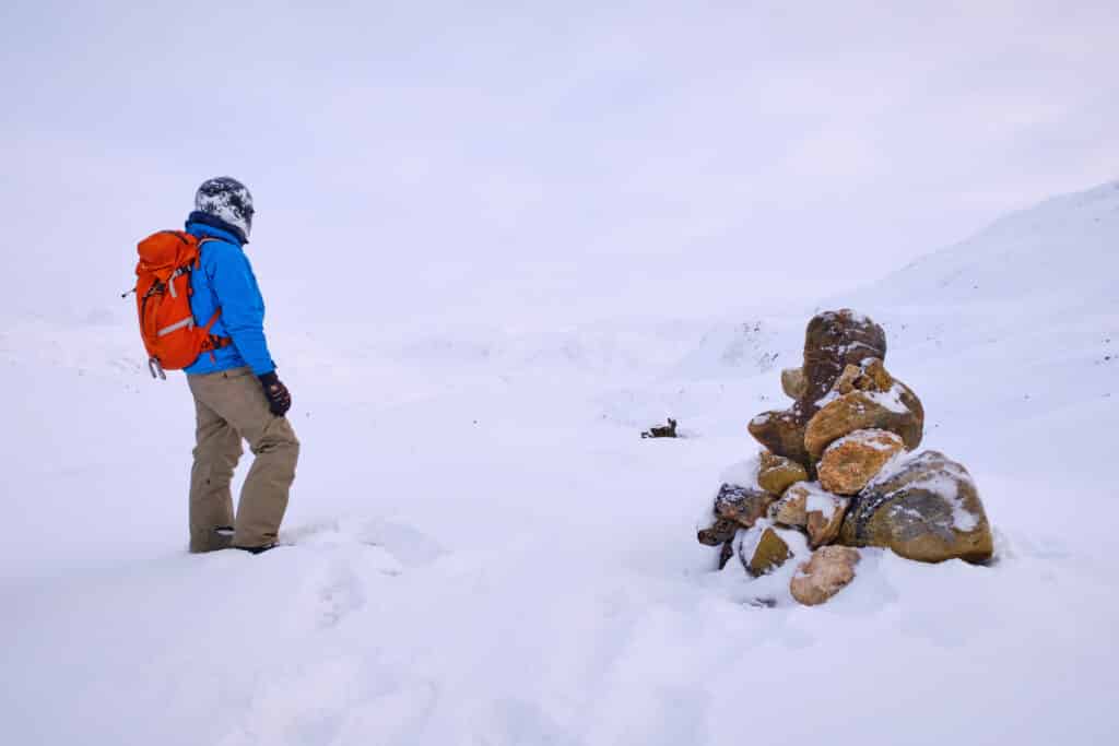 Person near one of the stone cairns that mark the Arctic Circle Trail route near Sisimiut