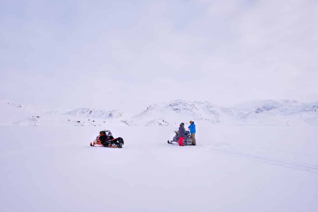 People having a Picnic lunch in the middle of the frozen Kangerlusarsuk Tulleq fjord near sisimiut on a snowmobile excursion